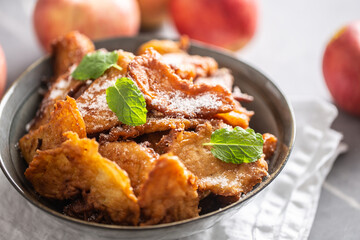 Finely fried apple pancakes sprinkled with vanilla sugar and cinnamon topped with mint leaves
