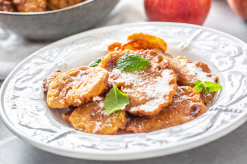Finely fried apple pancakes sprinkled with vanilla sugar and cinnamon topped with mint leaves