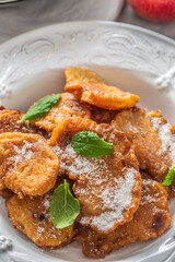 Finely fried apple pancakes sprinkled with vanilla sugar and cinnamon topped with mint leaves