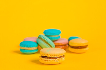 Sweet almond colorful unicorn pink blue yellow green macaron or macaroon dessert cake isolated on trendy yellow modern fashion background. French sweet cookie. Minimal food bakery concept Copy space