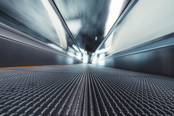 Long exposure shooting from the bottom of a moving walkway in an airport terminal; travelator...