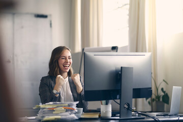 Cheerful businesswoman celebrating while looking at her computer, in her nice office space. 