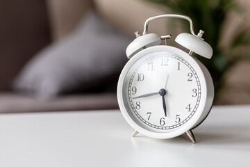 white clock with an alarm clock on the table