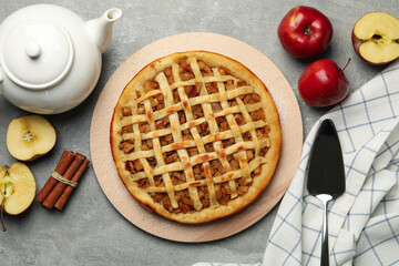Composition with apple pie and ingredients on gray background, top view
