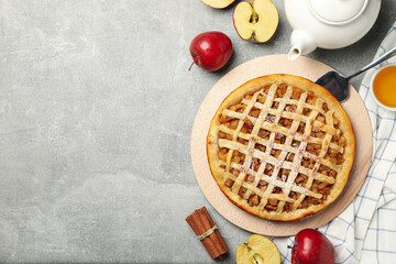 Composition with apple pie and ingredients on gray background, top view