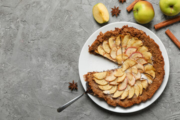 Composition with apple pie and ingredients on gray background, top view