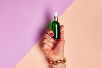 Female hand holding dropper with cosmetic serum.