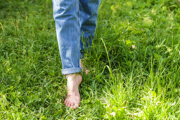 Two beautiful female feet walking on grass in sunny summer morning. Light step barefoot girl legs...