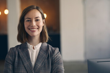 Portrait of attractive businesswoman in a suit smiling and looking into the camera while standing...