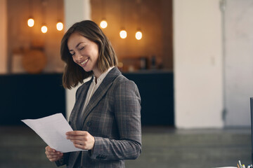 Portrait of young beautiful entrepreneur standing in a nice office building looking at paperwork...
