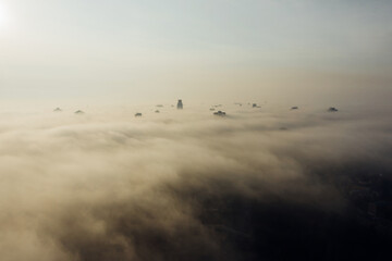 Naklejka premium Aerial view of the city in the fog. Skyscrapers above the fog