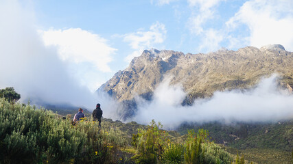 mountain landscape in the morning, two trekkers watching sunrise in Rwenzori Mountains in Uganda, Central Eastern Africa