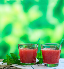 Watermelon juice glasses closeup view, blur green nature background