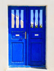 Blue wooden retro door on a whitewashed wall. Cyclades, Greece.