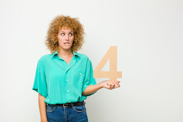young pretty afro woman surprised, shocked, amazed, holding a number 4.