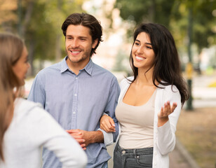 Obraz premium Girl Talking With Married Couple Of Friends Walking Outside