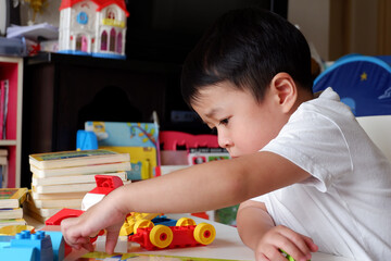An Asian boy is playing a toy on a white table.