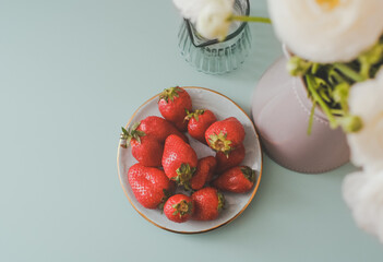 Fresh Strawberries and Flowers. Creative concept on Blue Background. Berries and White Ranunculus. Photo with film and grain effects