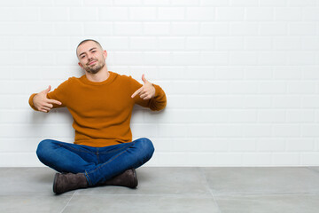young handsome man looking proud, arrogant, happy, surprised and satisfied, pointing to self,...