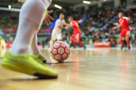 Futsal match - close up of ball in the corner and player's hand and legs.