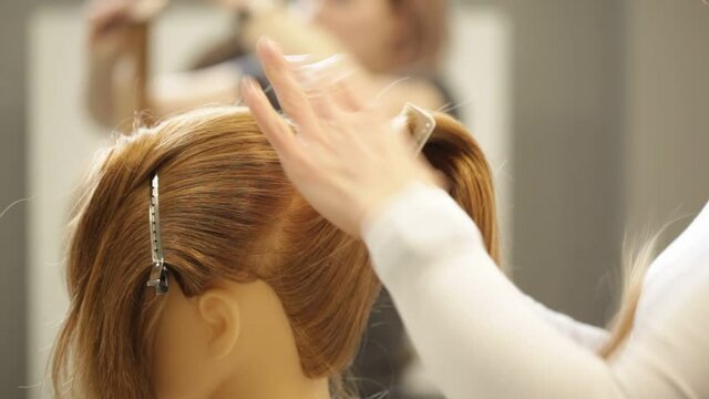 Hairdresser student combs mannequin long hair during training at hair academy
