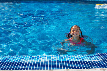 Top view of girl dressed red  swimsuit swimming in the blue resort pool Summer vacation concept