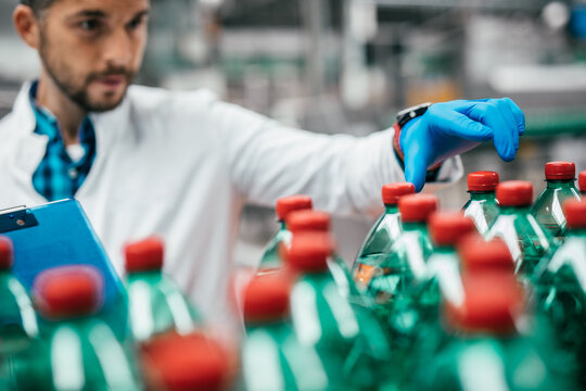 Male worker in bottling factory checking water ottles before shipment. Inspection quality control.