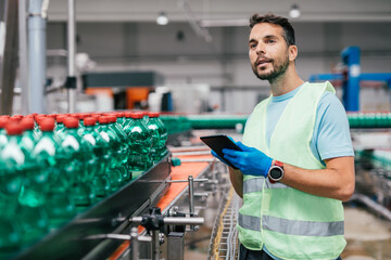 Male worker in bottling factory checking water ottles before shipment. Inspection quality control.