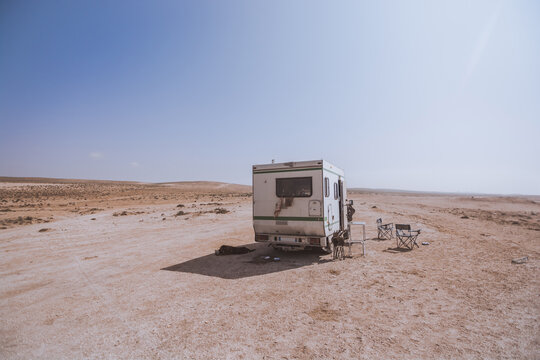 Old rusty camper van on sandy desert field. Camping site. Concept of wanderlust, freedom and outdoor adventure