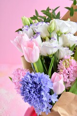 Beautiful spring flowers on pink background, selective focus, copy space. Bunch of tender tulips, eustoma flowers and hyacinthus. Romantic bouquet of flowers. 