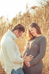 Happy pregnant couple enjoys life and relaxes in nature.