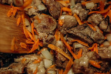 Onions with carrots are fried. Home cooking. Pilaf with meat