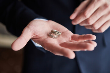 man holding wedding rings, groom getting ready in the morning before ceremony