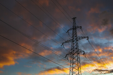 Transmission power tower on background of dramatic colorful sky. Lattice tower, used to support an overhead power line.