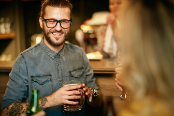Young handsome hipster holding beer and enjoying free time with friends.