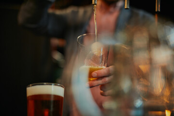 Closeup of man filling glass with beer.