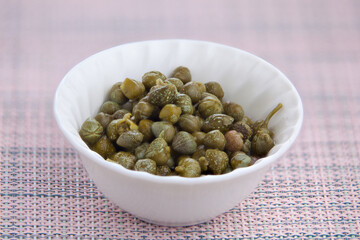 tasty salted italian capers on a plate on a wooden background