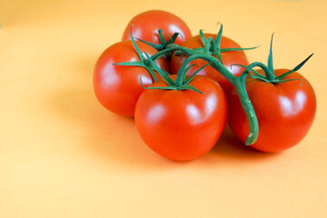 five ripe round red tomatoes in a bunch on a yellow background side view