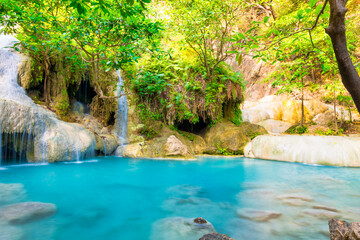 Naklejka premium Emerald blue lake with rock cascades of stream waterfall in tropical jungle forest. Landscape of Erawan National park, Kanchanaburi, Thailand
