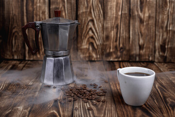 Steamed Moka pot with coffee beans on a dark wood table vintage photo