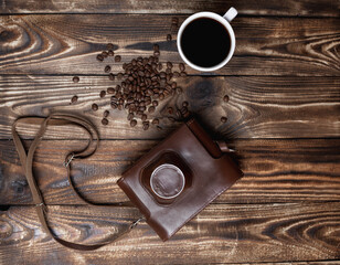 On a wooden table a cup of espresso coffee, a vintage camera and coffee beans