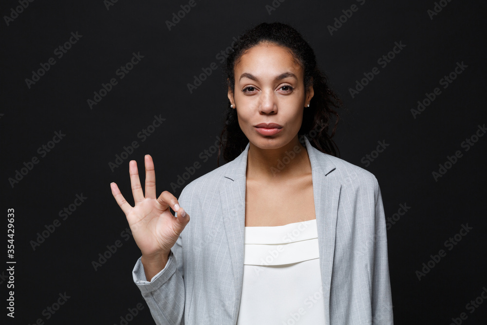 Wall mural beautiful young african american business woman in grey suit, white shirt posing isolated on black w