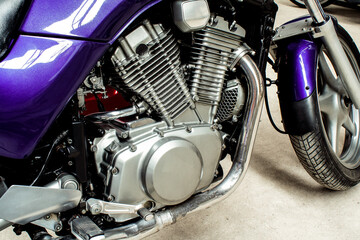 Fototapeta premium Silver v-twin shaped engine of sports motorcycle close-up. Pistons, cylinders, pedals, gearbox, front wheel motorbike. Chrome motor parts. Repair, bike maintenance in the garage.