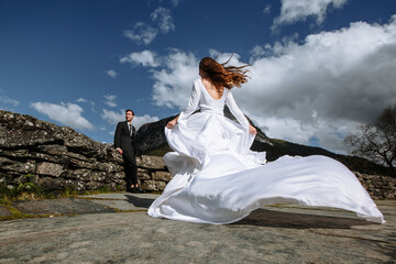 Newlyweds on the background of mountains. The bride in a long wedding dress runs to the groom