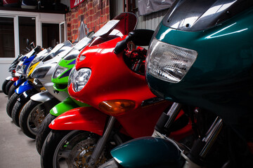 Colored sports, road beautiful bikes in a motor show, close up. Many motorcycles parked in a store. Sale of used cruise motorbikes in the cabin. Showroom equipment in the garage.