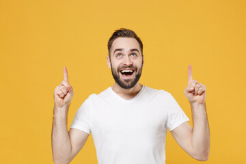 Excited young bearded man guy in white casual t-shirt posing isolated on yellow background studio...