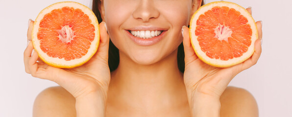 Banner happy beautiful woman with perfect white teeth hold red grapefruit slices in hands and smile isolated on white background. Young girl posing with citrus fruit. Cosmetology, diet, stomatology