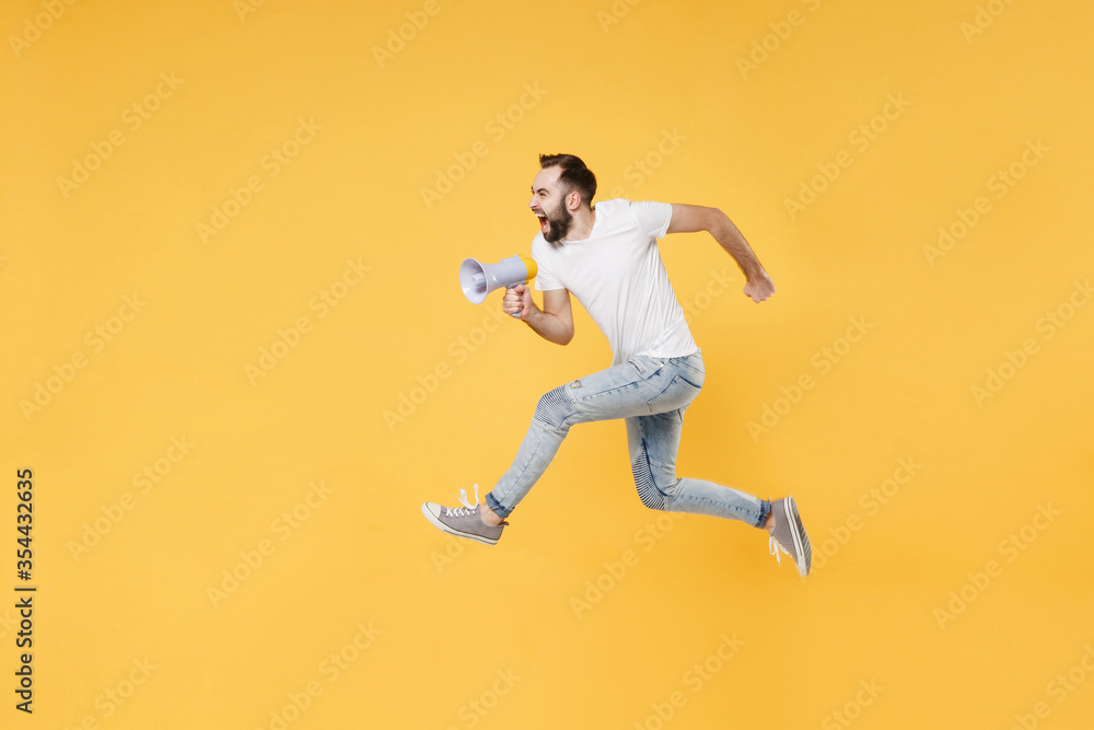 Wall mural crazy young bearded man guy in white casual t-shirt posing isolated on yellow wall background studio