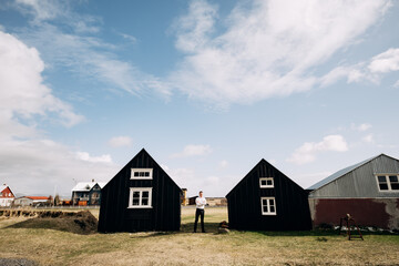 Fototapeta na wymiar A man in a white shirt between two wooden black houses. Destination Iceland wedding. 
