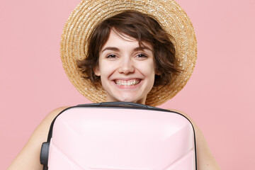 Smiling young tourist girl in hat posing isolated on pink wall background studio portrait. Female...